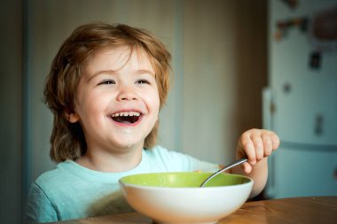 Çocuk yiyor. Küçük çocuk mutfakta kahvaltı yapıyor. Mutfakta meyve püre yiyen mutlu sevimli bebek gülümseyen. Aç küçük çocuk yeme.