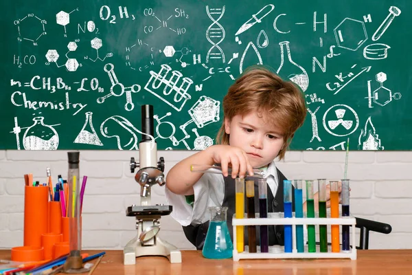 Vidám mosolygós kisfiú szórakozás a kék fal ellen. Első fokozat. Tudományos és oktatási koncepció. Saját kémia kísérlet. Kísérlet. Mit tanítanak a kémiában. — Stock Fotó