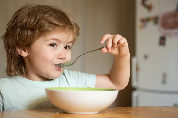 Mutfakta yemek yiyen bebek. Mutlu çocuk. Sevimli çocuk yiyor. Küçük bebek yiyor. Küçük çocuk mutfakta kahvaltı yapıyor. Aç küçük çocuk yeme. — Stok fotoğraf