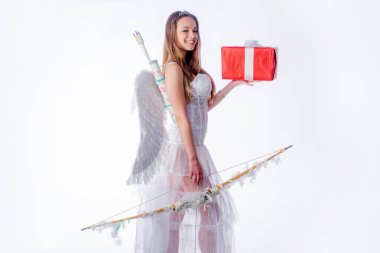 Beyaz arka plan izole edilmiştir. Sevgililer gününde Cupid. Işık arka planda bir melek gibi giyinmiş kız. Hediye ile bir Cupid küçük kız portresi.