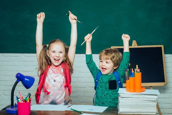 Zurück zur Schule - Bildungskonzept. fröhlich lächelnder kleiner Junge und süßes kleines Mädchen, die Spaß an der Tafel haben. Lustige kleine Kinder, die auf die Tafel zeigen. — Stockfoto