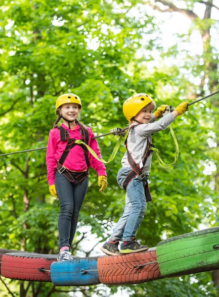 Small boy enjoy childhood years. Happy child boy calling while climbing high tree and ropes. Cute child in climbing safety equipment in a tree house or in a rope park climbs the rope. — Stock Photo, Image