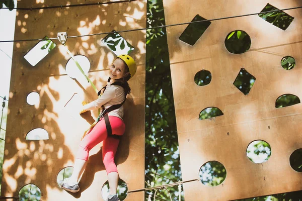 As cordas altas andam. Menino bonito da menina da escola desfrutando de um dia ensolarado em um parque de atividades de aventura de escalada. Vai à Aventura Macaco. Aventura escalada alto fio parque . — Fotografia de Stock