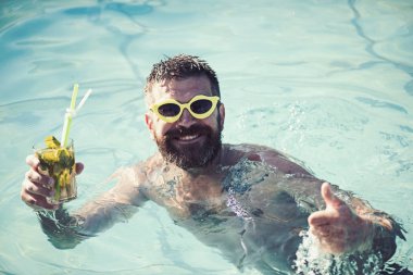 Zevk ve mojito kokteyl ile Yüzme havuzunda rahatlatıcı bir adam.