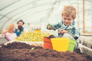 Kutusunda toprak tam oturuyor ve tencere ile zemin doldurma gülümseyen çocuk. Sarışın çocuk arkadan spade sera üst saat süre içinde oynamaktan