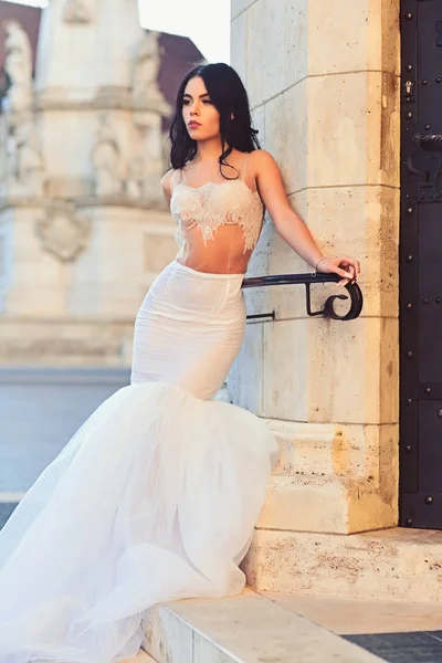 Fashion model or princess in dress. Bride girl at wedding ceremony in castle. Woman at stone ancient column in summer. Wedding fashion and beauty salon. Sexy girl in white dress with stylish hair — Stock Photo, Image