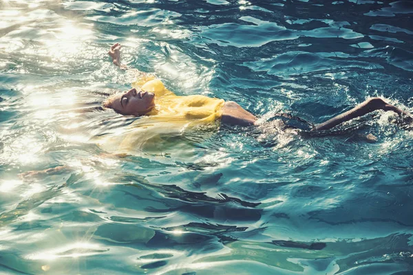Schöne junge Frau im sexy gelben Kleid schwimmt am Meeresstrand — Stockfoto