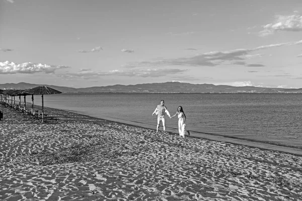 Pareja corriendo en una playa de arena al atardecer . — Foto de Stock