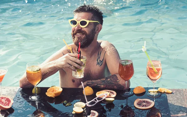 Chill out in summer swimming pool. chill out of bearded man with cocktails and fruit