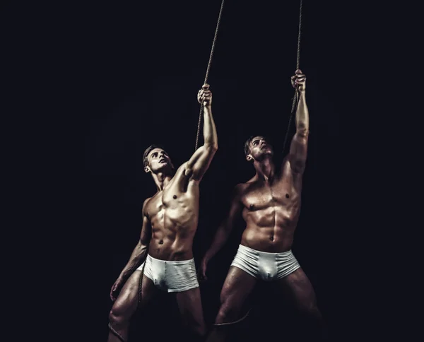 Fitness dieting and flexibility in acrobatics. Circus gymnasts at pilates or yoga training. Twins men with muscular body on rope. Sport workout for bodybuilder. Friendship of men do gymnastic — Stock Photo, Image
