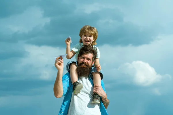 Generación. Padre llevando a su hijo de vuelta al parque. Padre e hijo construyendo juntos un avión de papel. Retrato de padre feliz dando hijo paseo a cuestas sobre sus hombros y mirando hacia arriba. —  Fotos de Stock