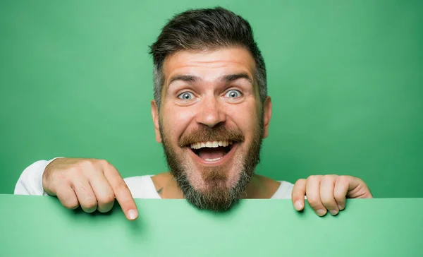 Homme barbu pointant sur le bureau vert. Traditions et célébrations en mars. La couleur verte de la St. Patricks jour. Un visage passionné d'hommes excités. Espace de copie. — Photo