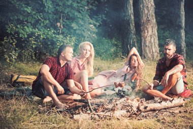 Ormanda, çifte randevu piknik aşık Genç çiftler. Adam ve arkadaşı kamp ateşi, arkadaşlık ve eğlence kavramı üzerinde Sosis kızartma sakallı