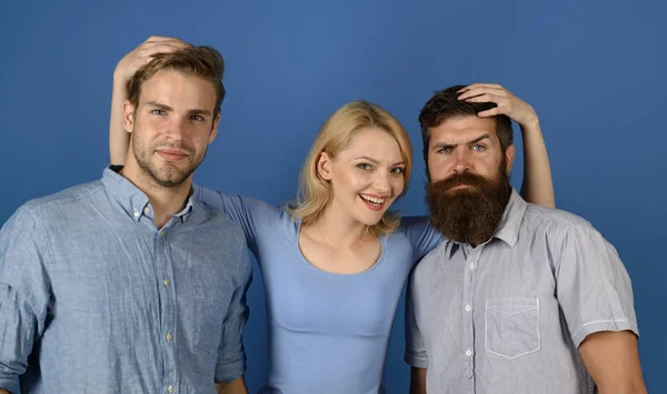 Relaciones amistosas. Chica y chicos felices juntos. La mujer abraza a dos hombres. Más que amigos. Verdadera amistad y relaciones humanas. Amigos del grupo abrazan fondo azul. Somos familia. Relaciones libres — Foto de Stock