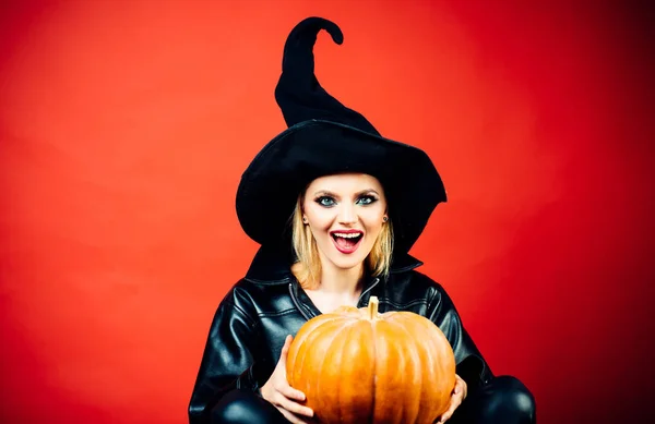 楽しいハロウィンをお過ごし下さい。赤い背景の上にパーティーに黒い魔女ハロウィーンの衣装を着た若い女性。ハロウィーンのコンセプト. — ストック写真