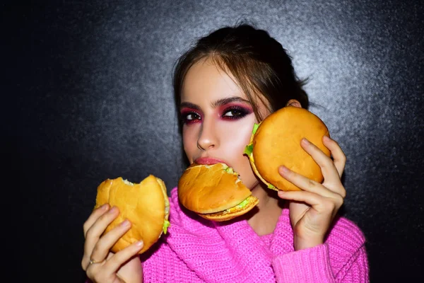 Moda, belleza.Mujer sexy con maquillaje perfecto comiendo hamburguesas. Concepto de belleza femenina . — Foto de Stock