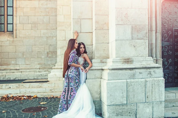 Сексуальні дівчата в одязі зі стильним волоссям. сексуальні дівчата позують на кам'яній колонці у весільній та модній сукні . — стокове фото