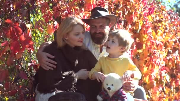 秋の家族おめでとう秋の自然の背景の上を歩く子供の息子と笑顔のカップル。ロマンチックなカップル公園で黄色い秋の自然の中で一緒にリラックスピクニックをする陽気な家族. — ストック動画