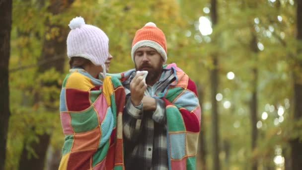 Kranke haben eine laufende Nase. Frau macht Heilmittel gegen Erkältung im Herbst Park. Mann mit Allergie-Symptomen pustet Nase. — Stockvideo