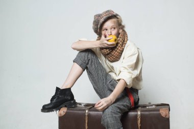 Eski bavulla seyahat edin. Homelss, ne kadar çok şey var? bere eski moda çocuk elma yemek. retro model. Vintage askı. retro erkek takım elbiseli genç kız. Kirli suratlı sokak çocuğu. vintage İngilizce tarzı