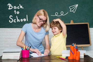 Okula geri dön. Öğretmen okulda sınıfta ödevlerini çocuklara yardım ediyor. İlkokuldaki çocuklar.
