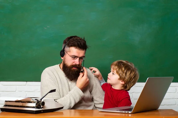 Elementary school teacher and student in classroom. Teacher and schoolboy using laptop in class. Young adult concept. Daddy and son together. Childhood and parenthood. Copy space — Stock Photo, Image