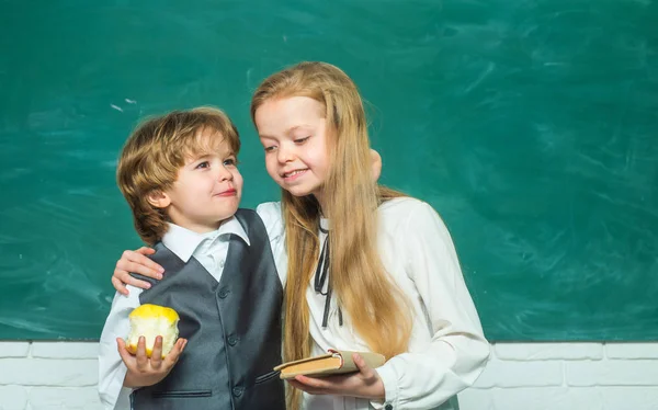 Elementary school and education. First grade. Elementary school kids in classroom at school. September 1. Schoolchild. Teacher and child. School kids against green chalkboard.