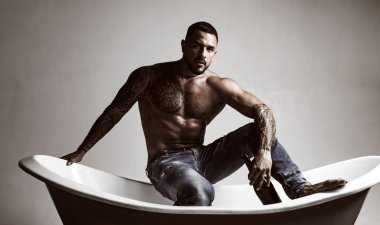 Bu da banyo zamanı demek. Banyoda oturan kas gövde dövmesi ile güçlü latino adam. Atelak İspanyol adam banyoda şarap içiyor. Şarap ve banyo onun için rahatlamanın anahtarıdır.