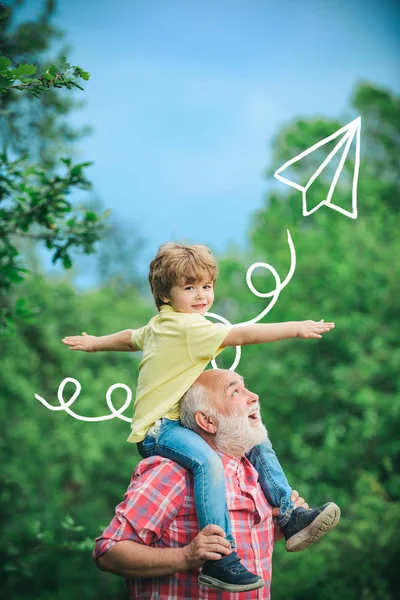 Grand-père parle à son petit-fils. Petit garçon et grand-père levant la main sur le ciel couchant profitant de la vie et de la nature. Papa et garçon souriant et câlin . — Photo