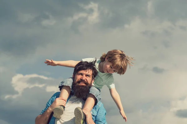 Padre e figlio. Tempo di famiglia. Papà e figlio. Ragazzo felice che gioca - aereo. Ritratto di padre felice che fa cavalcare il figlio sulle spalle e alza lo sguardo . — Foto Stock