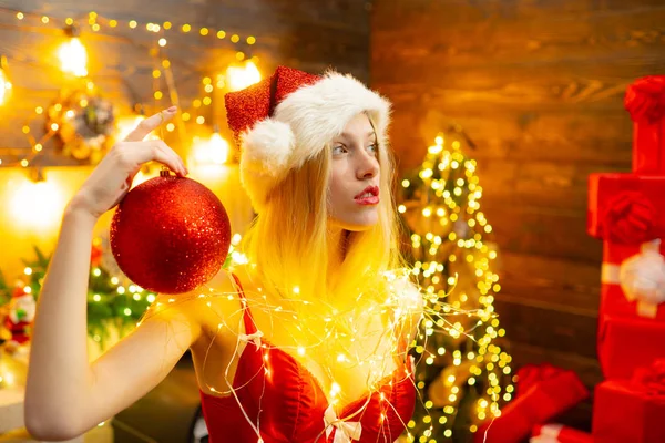 Lingerie rouge pour Noël. Sexy fille érotique célébrer le nouvel an et joyeux Noël. Lingerie sexy célébration de Noël. Aimez la paix et la joie pour toute l'année. Chapeau de fille santa à la maison près de l'arbre de Noël — Photo