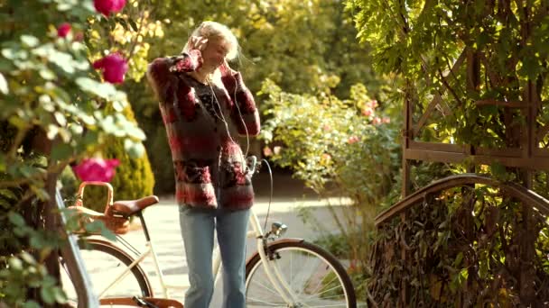 Écoutez de la musique dans les écouteurs, la musique du téléphone. Femme qui s'amuse au parc et sourit. Concept casque. Printemps personnes heureuses et joie. Belle femme écoutant de la musique sur une prairie . — Video