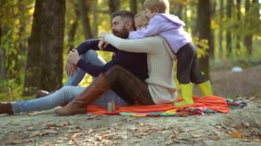 Renkli sonbahar aile portresi. Küçük oğlu sonbahar yaprakları döşeme ile mutlu gülümseyen genç anne. Genç ebeveynler ve çocuklar piknik yapıyor ve sonbahar güneşli bir günde birlikte dinleniyor.