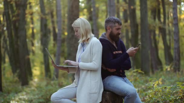 Geschäft im Freien. Paar arbeitet - mit Laptop und Smartphone im Freien. Verliebte auf herbstlichem Hintergrund. Herbstreisen. Fröhliches, unbeschwertes Herbstpaar an sonnigem Tag im Park. — Stockvideo