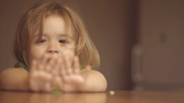 Anak kecil sedang sarapan di dapur. Potret manis tertawa bayi laki-laki kecil dengan rambut pirang makan dari piring memegang sendok dekat . — Stok Video