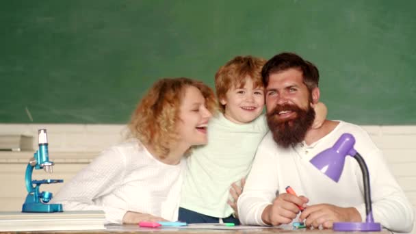 Jong stel helpt zijn zoon om huiswerk te maken. Onderwijs voor kinderen buiten school. Leerling van de basisschool studie binnenshuis. Gelukkig schoolkinderen in les in 1 september. Vrouw en man helpt kind jongen. — Stockvideo