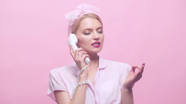 Chica pin-up feliz posando con el teléfono sobre fondo rosa. Asegura a la joven con el teléfono. Agente de servicios al cliente . — Vídeo de stock