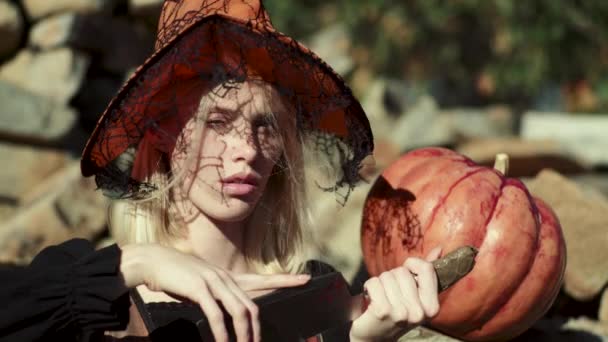 Halloween vrouw. Mooie jonge verrast vrouw in Witch hat en Halloween kostuum houden pompoen. Mooi meisje vieren Halloween. — Stockvideo