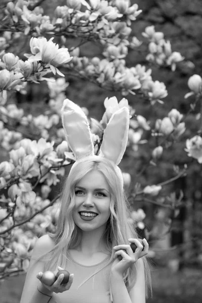 Mulher com ovos de Páscoa em orelhas de coelho em flor de magnólia — Fotografia de Stock