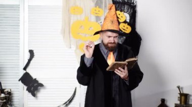 Sihir, büyü, sihir kitabı. Sakallı sihirbaz sihir hakkında eski bir kitap okur. Cadılar Bayramı Sihirbazı. Sihirbaz Cadılar Bayramı'nda gizli bir kitap okur. Mistik profesör. Eğlenceli yaratıcı eğitim. Cadılar Bayramı şapkası.