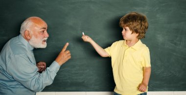 Baba oğluna okulda sınıfta ders veriyor. Yaratıcı genç gülümseyen Öğrenci portresi. Baba oğul soruna odaklanmış. Eski öğretmen.