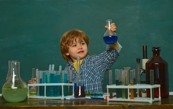 Child in the class room with blackboard on background. Learning at home. Chemistry The Science Classroom. Little kids scientist earning chemistry in school lab