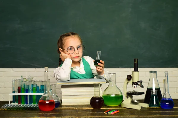 Kid lär sig i klass på bakgrund av Blackboard. Biologi experiment med Mikroskop. Vetenskaps-och utbildningskoncept. Kemi lektion. — Stockfoto