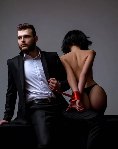 Sexy girl naked buttocks. Passionate lovers. Sex domination. Sex submission. Macho well groomed hipster and naked sexy woman tied hands red ribbon. Sexual relations. Sex game. Tease and seduce — Stock Photo, Image