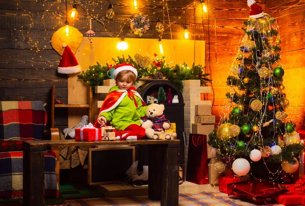 Lindo niño pequeño jugar cerca del árbol de Navidad. Regalos y sorpresas. Feliz Navidad y feliz año nuevo. Los niños disfrutan de las vacaciones de invierno en casa. Navidad del día de familia. Hogar lleno de alegría y amor —  Fotos de Stock