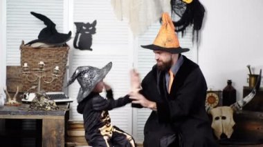 Baba ve oğul evde eğleniyor. Mutlu Aile Cadılar Bayramı'na hazırlanıyor. Babam ve çocuğum mutlu. Cadılar Bayramı geçmişi. Bir cadılar bayramı arka plan üzerinde komik karnaval kostümleri ile Tatil.