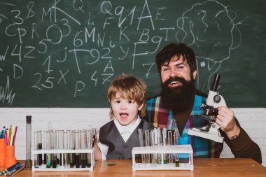 Sınıfta mikroskop kullanan öğretmen ve öğrenci. İlk okul günü. Eğitim. Test tüpüyle deney yapan mutlu küçük bilim adamı. Ders.