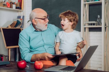 Dünya Öğretmenler Günü. Mutlu sevimli Torun ve Büyükbaba kapalı bir masada oturuyor. Okula geri dön. Öğrenme ve eğitim kavramı.
