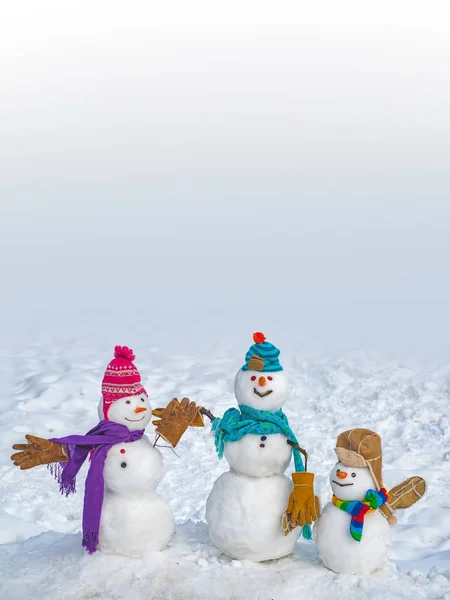 Szczęśliwy bałwan z pudełka na prezenty stojące zimą krajobraz Bożego Narodzenia. Zabawny bałwan z marchewką zamiast nosa i w ciepłym dzianinowej czapce na śnieżnej łące na niewyraźne tło śniegu. — Zdjęcie stockowe