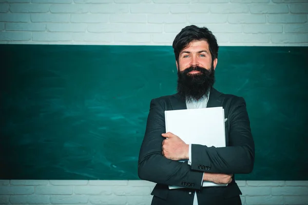 Leraren dag-kennis en educatieve school concept. Jonge bebaarde leraar in de buurt van schoolbord in school klas. Wereld leraren dag. — Stockfoto